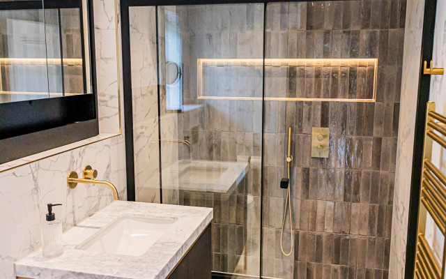 Elegant gold and black vanity paired with a walk-in shower, creating a luxurious bathroom atmosphere.