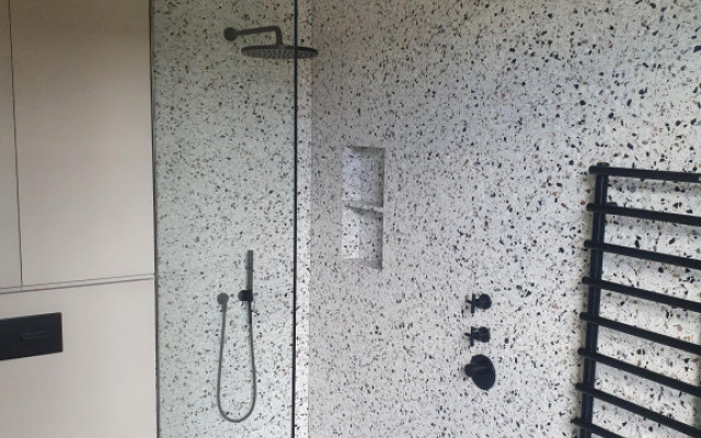 Stylish walk-in shower with sleek black radiator and contemporary design elements.